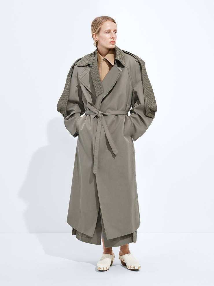 Input: a belted gabardine trench with woven leather panels, layered over a shirt and wide trousers